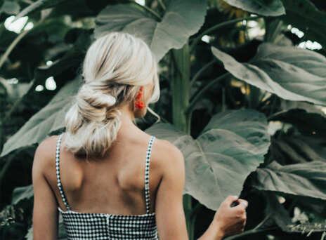 Ξανθιά γυναίκα γυρισμένη πλάτη με μαζεμένα μαλλιά σε χαμηλό κότσο