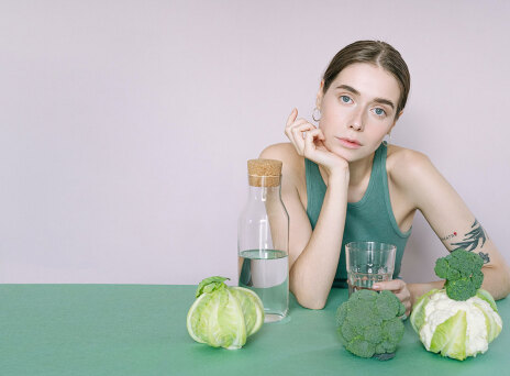 Καθιστή κοπέλα με λαχανικά μπροστά της