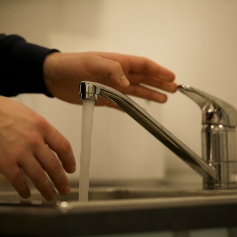 Βρύση με νερό και χέρι που πλένεται