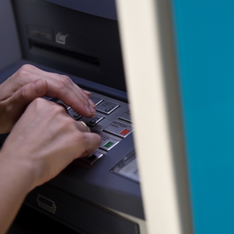 Άτομο μπροστά σε ΑΤΜ πληκτρολογεί τον κωδικό της κάρτας του
