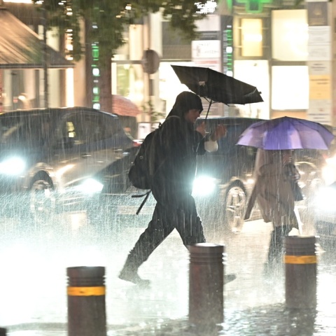 Πολίτες εν μέσω κακοκαιρίας περπατούν σε δρόμο της Αθήνας