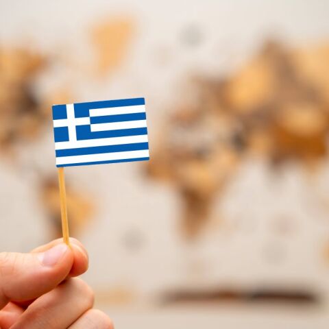 Ελληνικό σημαιάκι μπροστά σε έναν παγκόσμιο χάρτη