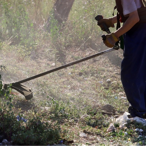 Άτομο με χορτοκοπτικό καθαρίζει οικόπεδο