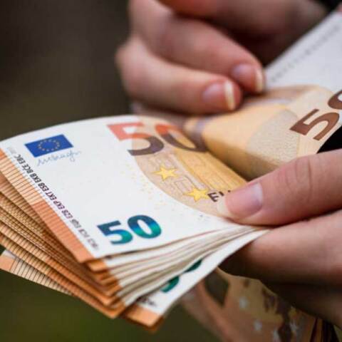 Άνδρας μετρά χαρτονομίσματα του ευρώ