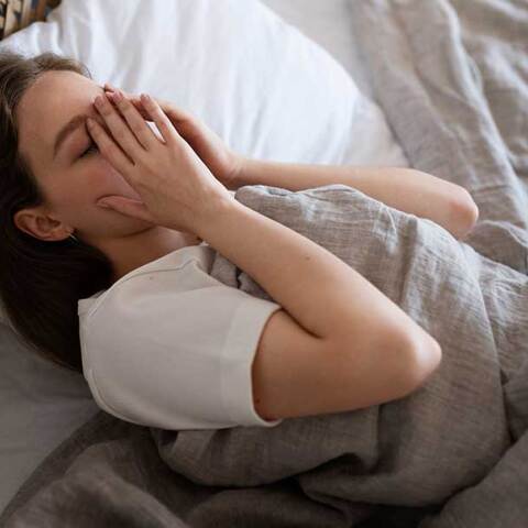 Γυναίκα στη μία πλευρά του κρεβατιού δυσκολεύεται να κοιμηθεί