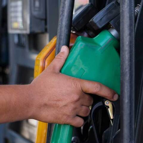 Υπάλληλος σε βενζινάδικο πιάνει την αντλία για να γεμίσει βενζίνη το ρεζερβουάρ του αυτοκινήτου