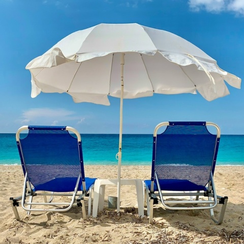 Παραλία στη Λευκάδα με δύο ξαπλώστρες και μία ομπρέλα καρφωμένη στην άμμο