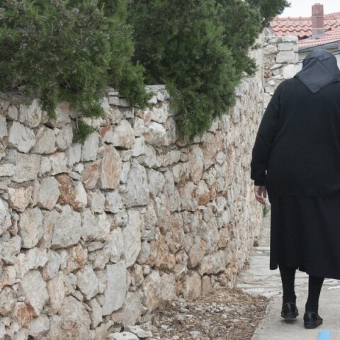 Ηλικιωμένη με μπαστούνι περπατά σε σοκάκι