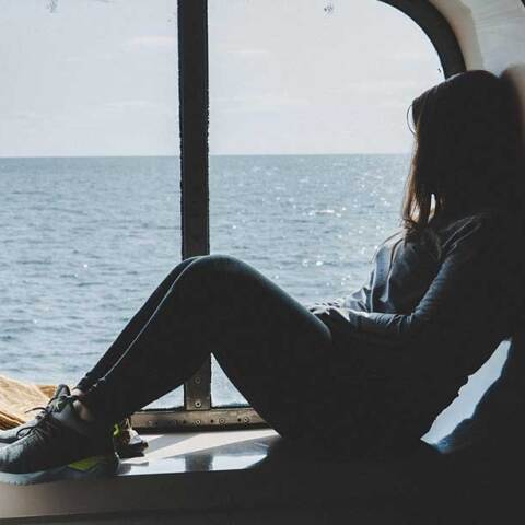 Επιβάτης μέσα σε πλοίο κάθεται μπροστά στο παράθυρο καμπίνας