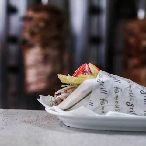 Σουβλάκι σε πάγκο ψητοπωλείου με φόντο τον γύρο