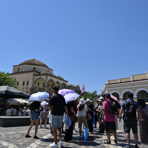 Πολίτες με ομπρέλες και καπέλα υπό καυτό ήλιο στην πλατεία Μοναστηρακίου