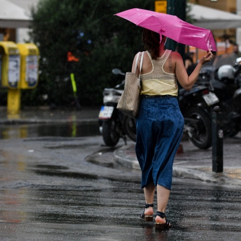 Γυναίκα με ομπρέλα εν μέσω καλοκαιρινού μπουρινιού