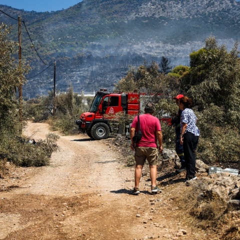 Πυροσβεστικό όχημα και πολίτες δίπλα σε αυτό με φόντο καμένη έκταση στο βάθος της φωτογραφίας