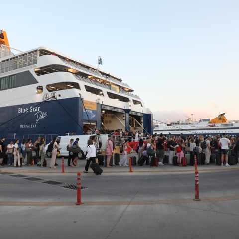Ταξιδιώτες μπροστά από τον καταπέλτη πλοίου στο λιμάνι του Πειραιά