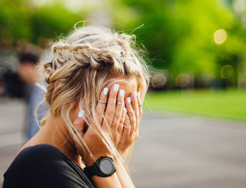 Κοπέλα κρύβει το πρόσωπό της με τα χέρια της