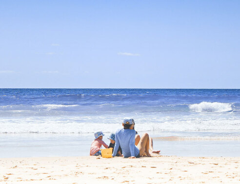 Οικογένεια κάθεται στην παραλία στην αμμουδιά