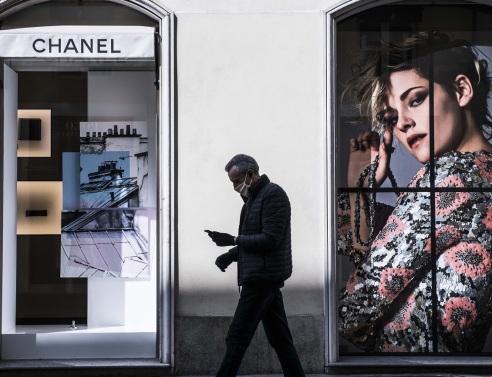 Άντρας με προστατευτική μάσκα περνάει έξω από κατάστημα Chanel