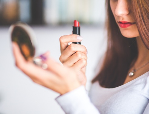 Γυναίκα κρατάει καθρεφτάκι και κόκκινο κραγιόν