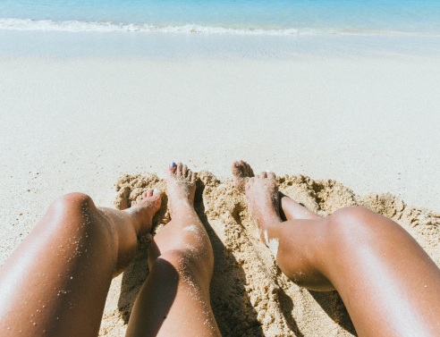 Γυναικεία πόδια στην άμμο παραλίας