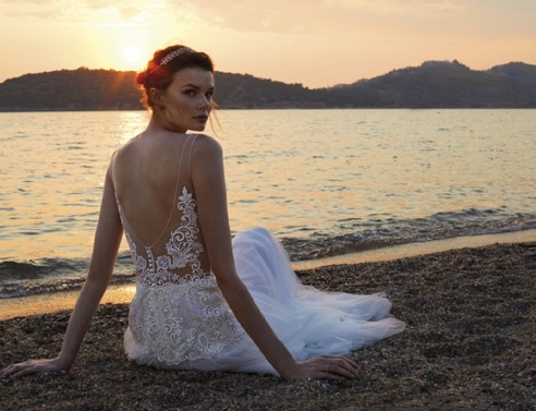 Κοπέλα με νυφικό καθισμένη στην άμμο