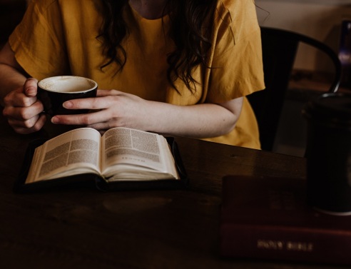 Κοπέλα διαβάζει βιβλίο και κρατάει καφέ