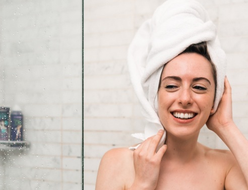 Κοπέλα με πετσέτα στα μαλλιά και το σώμα βγαίνει από το ντους