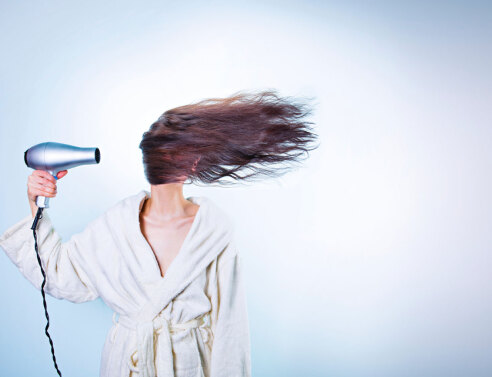 Κοπέλα με σεσουάρ φυσάει τα μαλλιά της