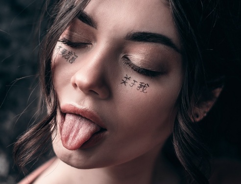 Πορτραίτο μελαχρινής κοπέλας με κλειστά μάτια και τη γλώσσα έξω