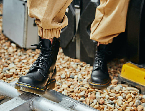 Φωτογραφία εστιασμένη σε πόδια που φορούν μαύρα μποτάκια