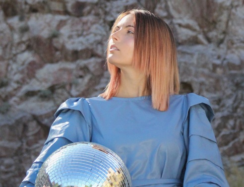 Κοπέλα με μπλε ρούχα και ξανθοχάλκινα μαλλιά με γυρισμένο πρόσωπο στα αριστερά