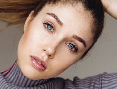 Γυναικείο πρόσωπο με μπλε μάτια και καστανά μαλλιά πιασμένα αλογοουρά