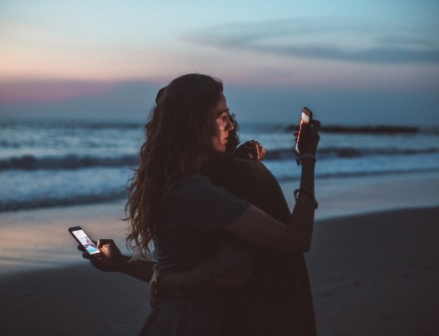 Ζευγάρι αγκαλιά κοιτάζει τα κινητά του