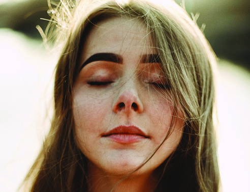 Πορτραίτο νέας κοπέλας με καστανά μαλλιά και κλειστά μάτια