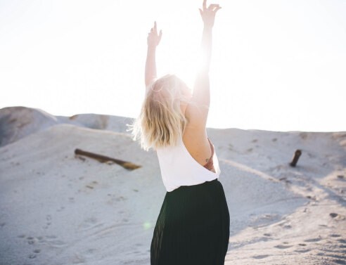 Κοπέλα με υψωμένα τα χέρια και φόντο τον ήλιο