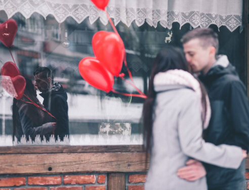 Ζευγάρι μπροστά σε βιτρίνα κρατάει μπαλόνια σε σχήμα καρδιάς