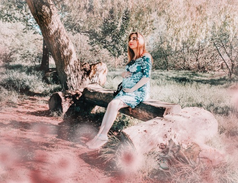 Έγκυος γυναίκα κρατά την κοιλιά της σε δάσος