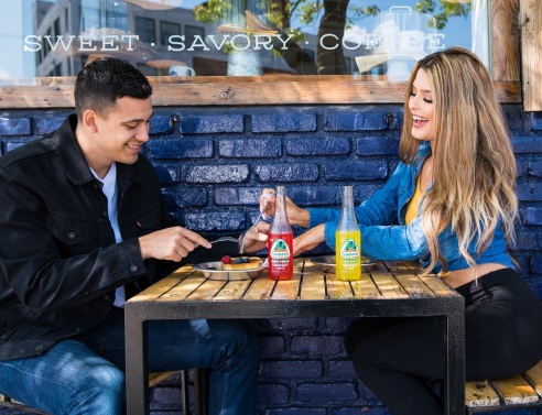 Άντρας και γυναίκα κάθονται σε τραπέζι σε εξωτερικό χώρο με φαγητό και ποτά