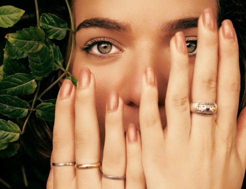 Κοπέλα κρατά τα χέρια της μπροστά στο πρόσωπο δείχνοντας τα νύχια της