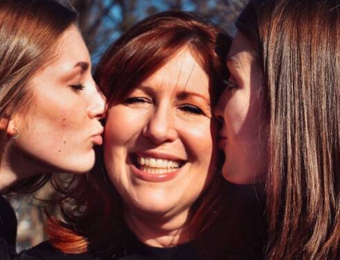 Δύο κόρες φιλάνε τη μητέρα τους στο μάγουλο