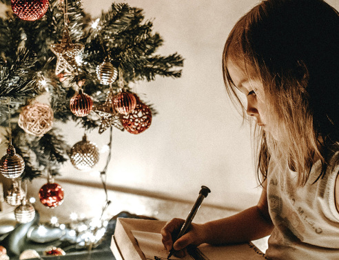 Μικρό κοριτσάκι δίπλα στο χριστουγεννιάτικο δέντρο