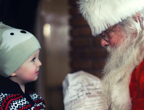 Ένα μικρό παιδάκι στέκεται μπροστά από τον Άγιο Βασίλη