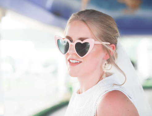 Ξανθιά κοπέλα ντυμένη νύφη με γυαλιά ηλίου σε σχήμα καρδιάς