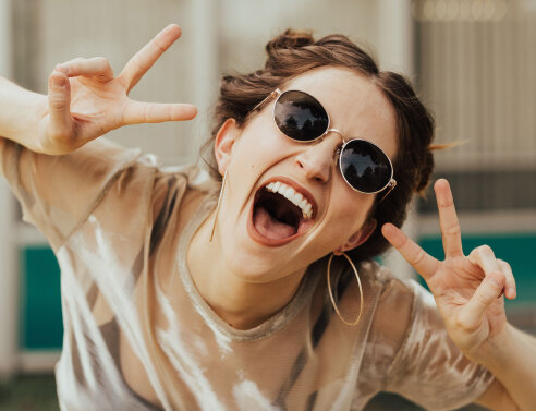 Κοπέλα με γυαλιά ηλίου που γελάει στην κάμερα