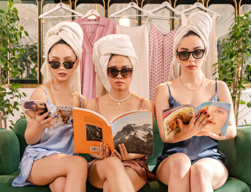 Τρεις γυναίκες με μαύρα γυαλιά ηλίου και πετσέτα τυλιγμένη στο κεφάλι καθισμένες σε καναπέ διαβάζουν περιοδικά