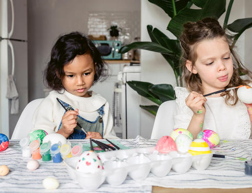 Δύο μικρά κοριτσάκια βάφουν πασχαλινά αυγά