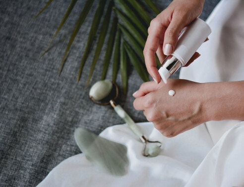 Γυναικεία χέρια. Το ένα κρατάει ένα μπουκαλάκι και βάζει κρέμα στο άλλο