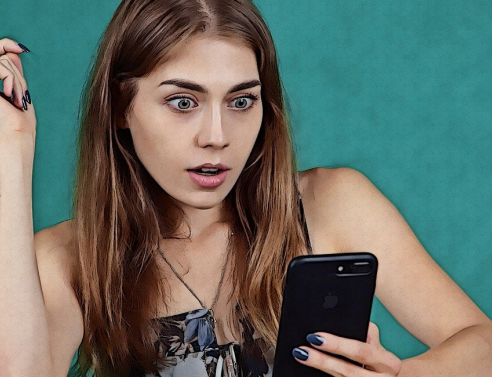 Γυναίκα κοιτάει σοκαρισμένη το κινητό της