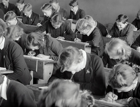 Ασπρόμαυρη φωτογραφία μαθητών σε θρανία να γράφουν διαγώνισμα