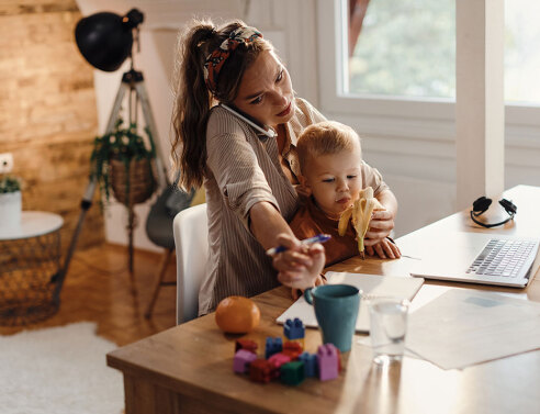 Γυναίκα μιλάει στο τηλέφωνο και κρατάει παιδί