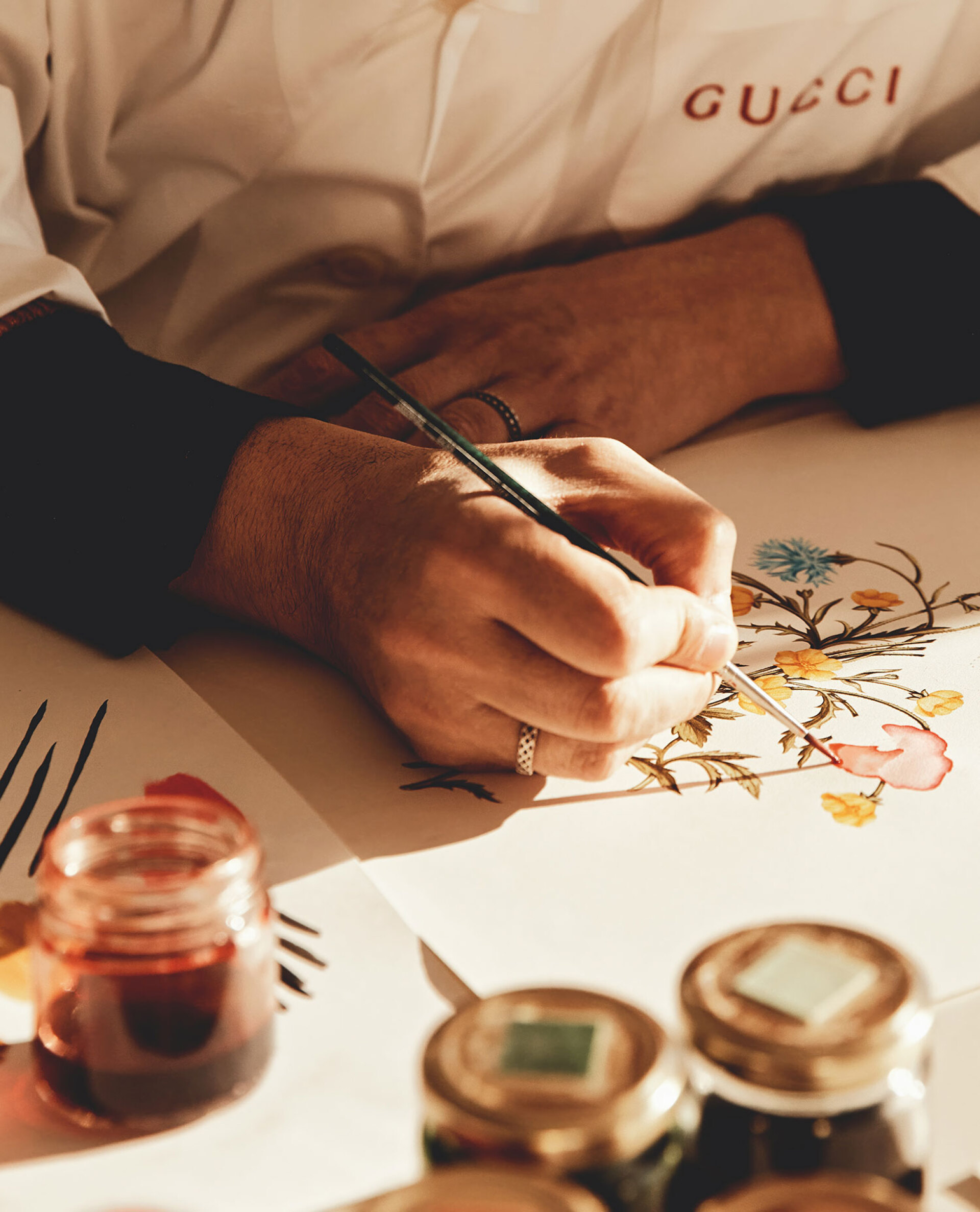 O καλλιτέχνης ζωγραφίζει το φλοράλ σχέδιο για ένα μεταξωτό μαντίλι στο ατελιέ του Οίκου στο Μιλάνο © Oliver Pilcher